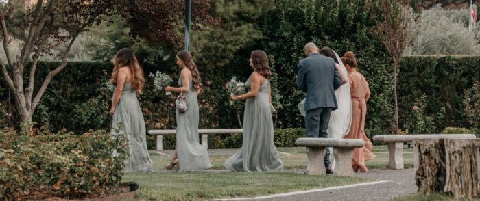 Tres damas de honor con vestidos verdes preceden a la novia que va detrás acompañada por sus padrinos