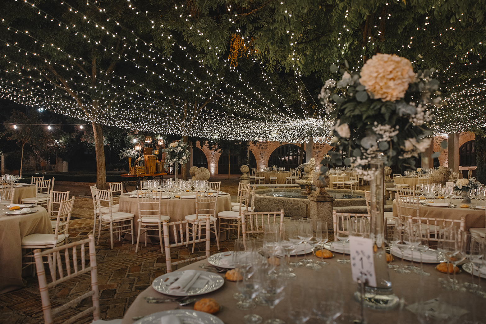 Claustro del Cigarral del Ángel cubierto de micro luces led con mesas montadas para una boda por la noche